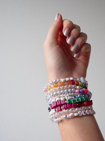 hand with a bunch of colorful beaded bracelets on the wrist