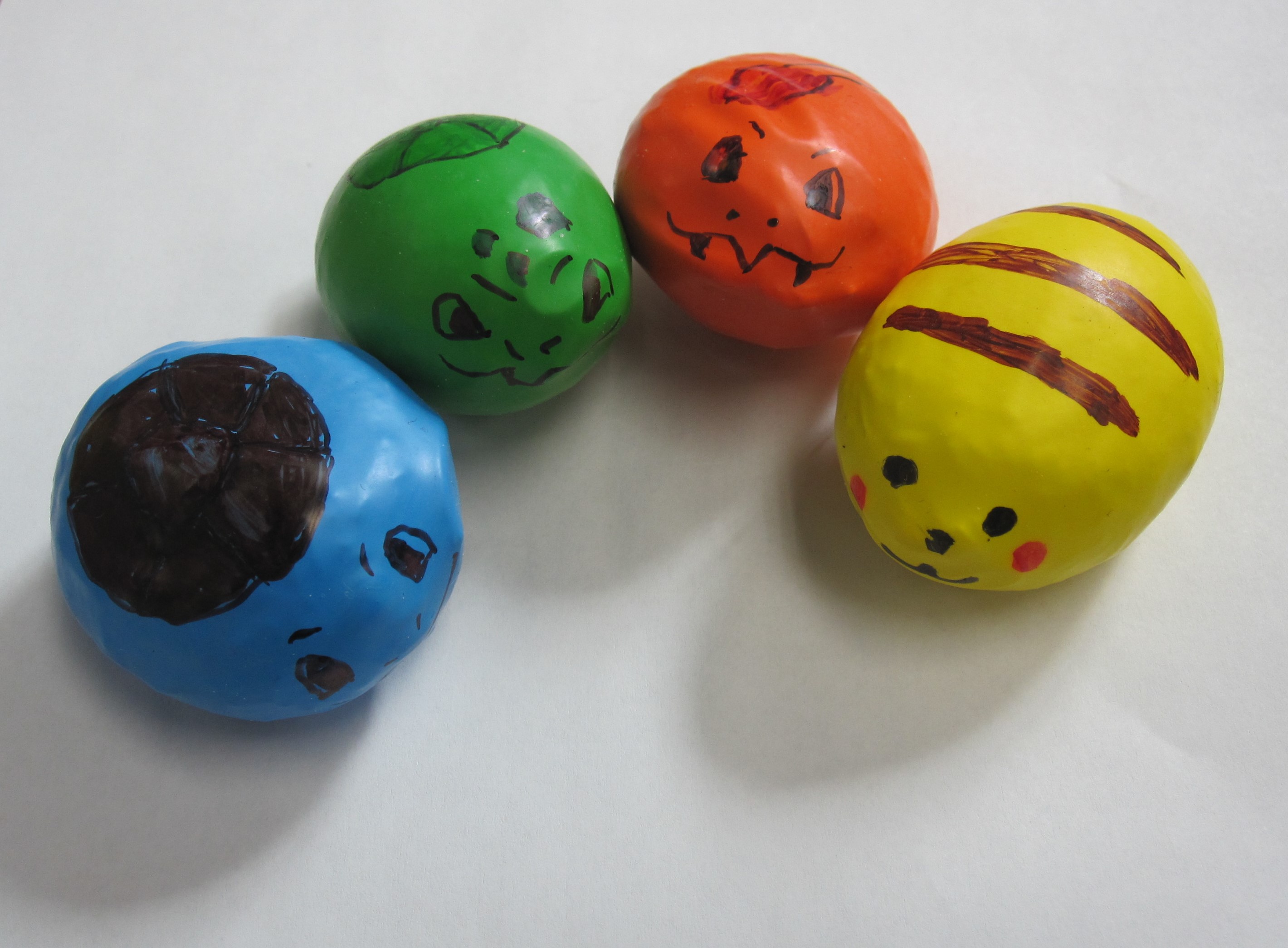 blue, green, orange, and yellow stress balls with drawn faces