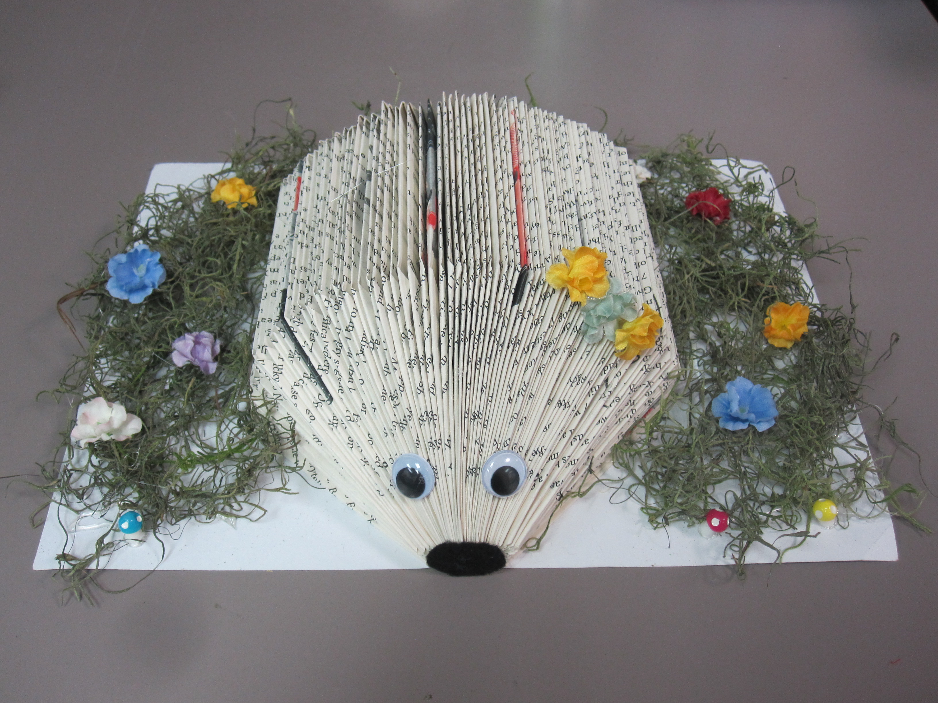 book hedgehog with flowers and moss