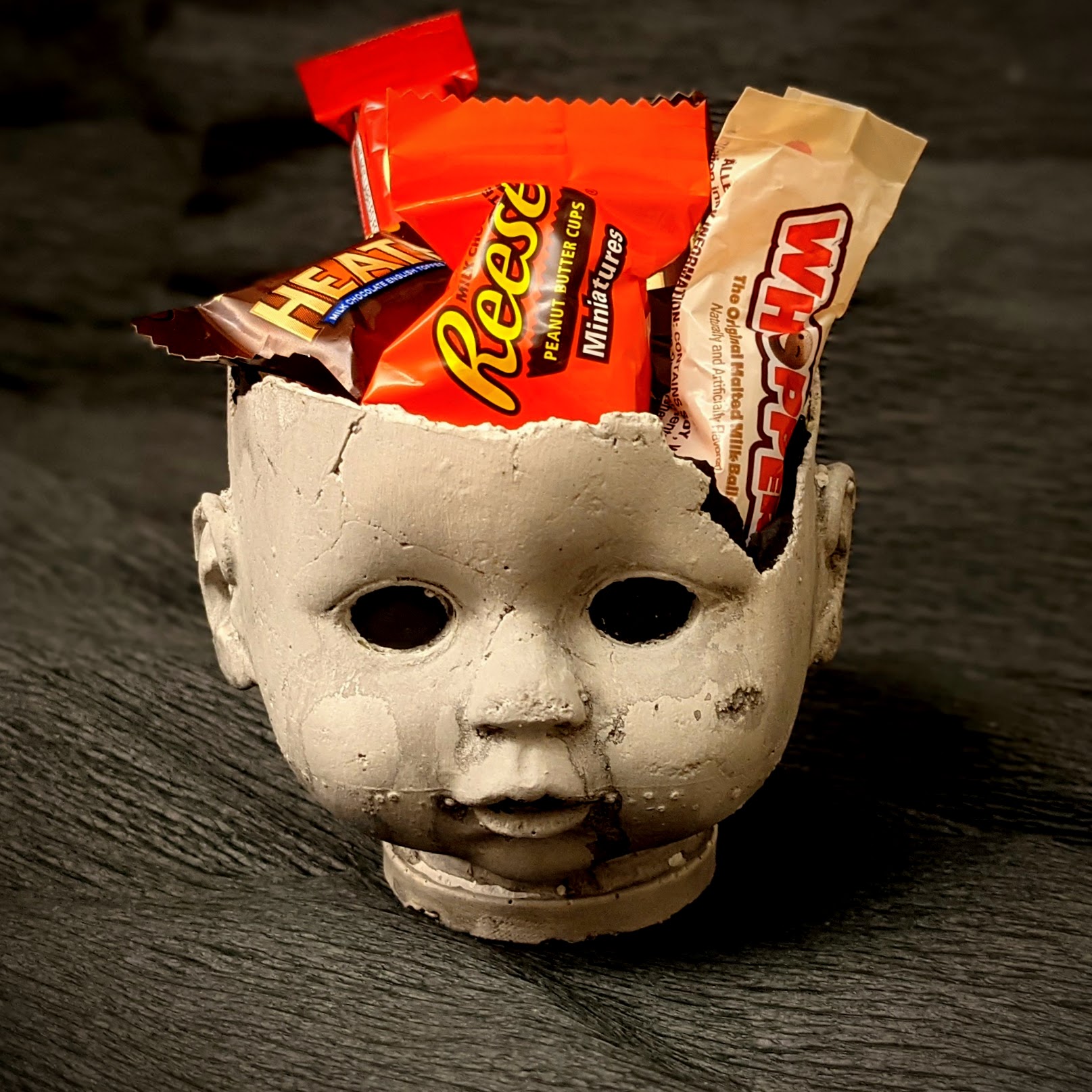 Cement baby doll headed holding candy 