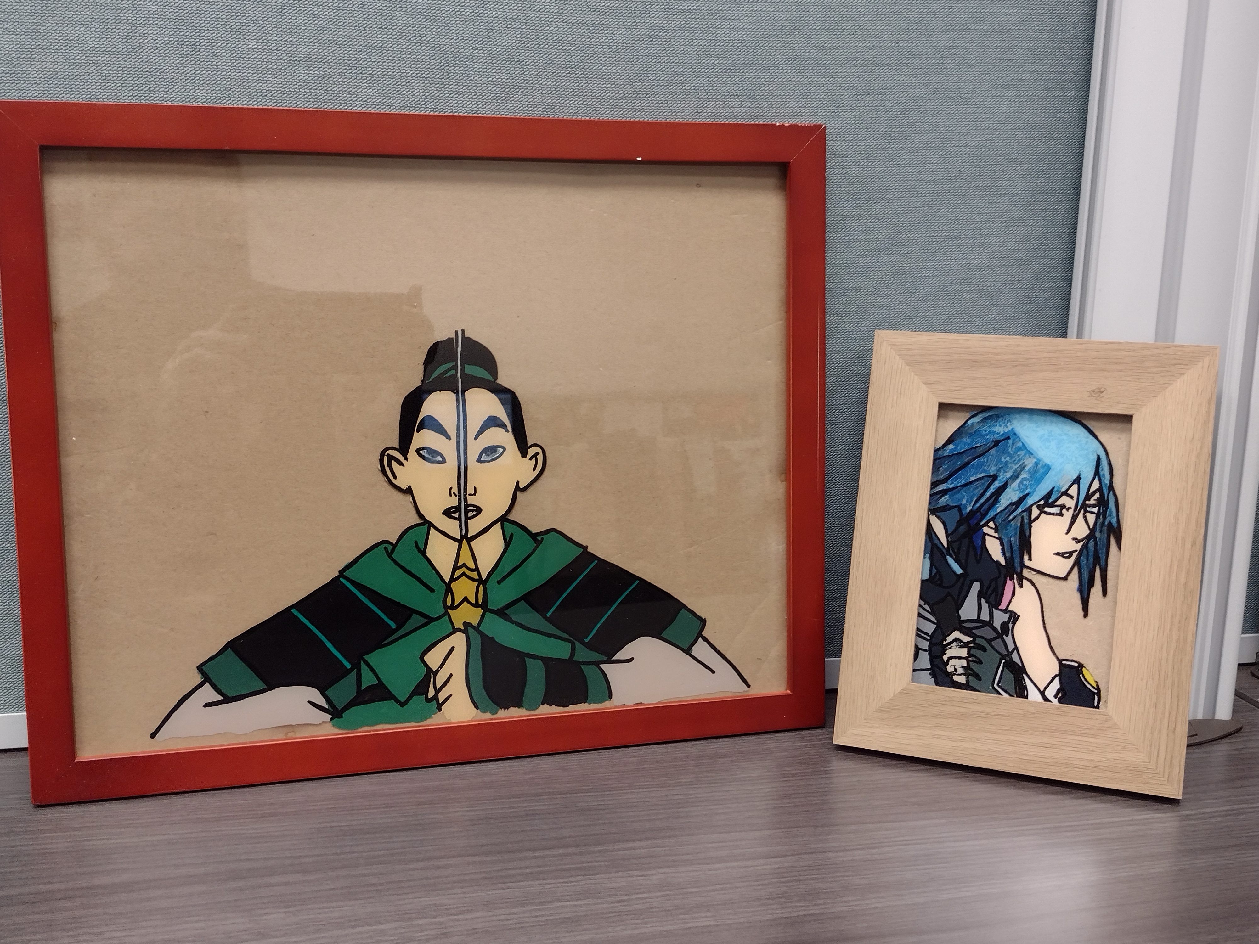 One large picture frame depicting a painted image of Disney's M<ulan holding a sword dressed in armor. Next to it is a smaller picture frame featuring a painting of Kingdom Hearts' Aqua.