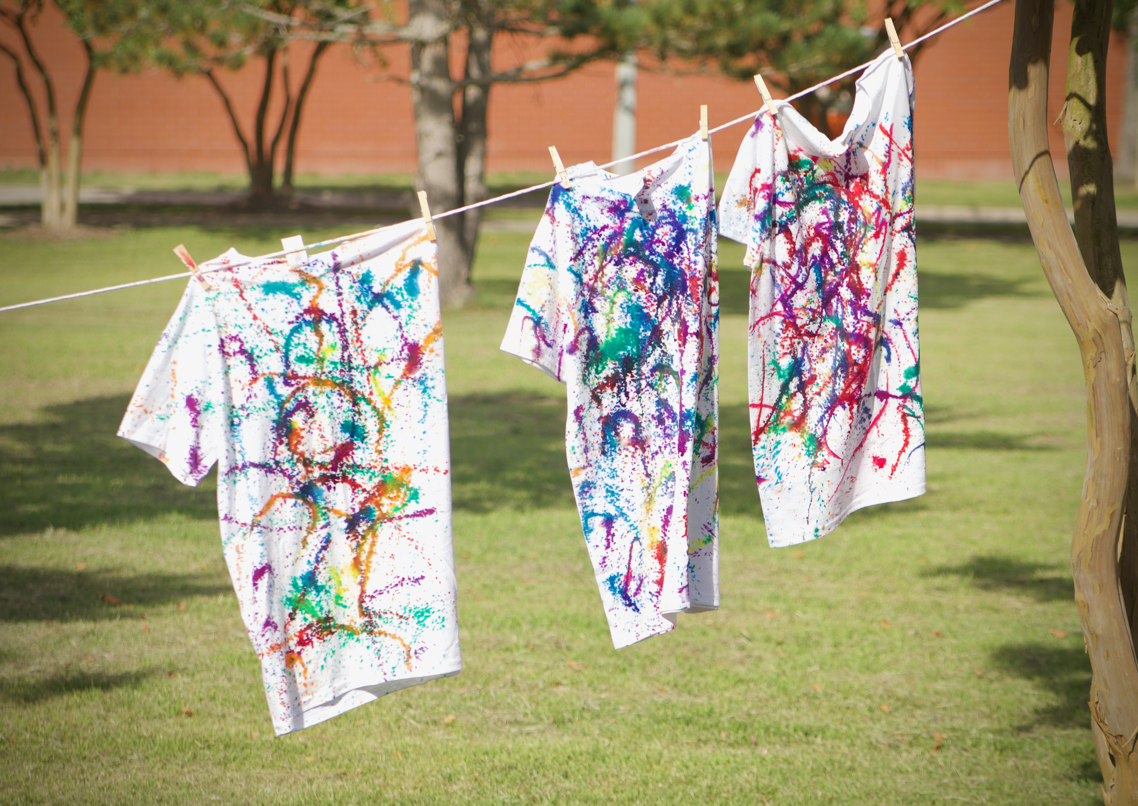 A photo of a clothesline with three shirts. All the shirts have varying levels of tie-dye.