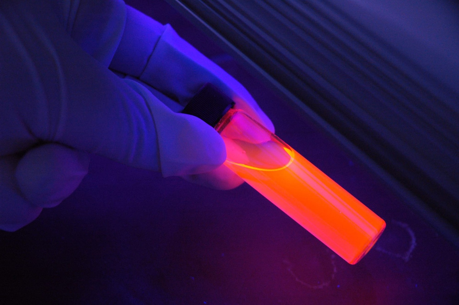 glowing orange test tube held in a gloved hand