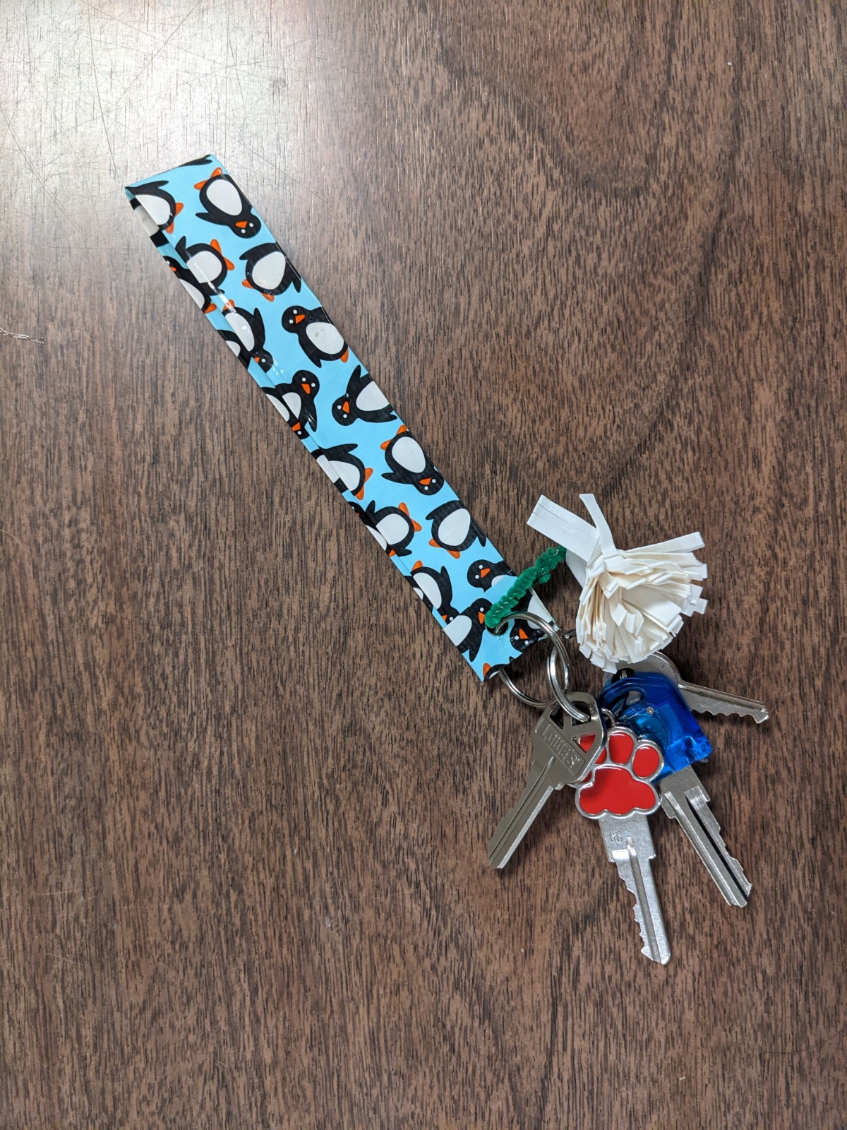 penguin on light blue duct tape keychain with keys and white duct tape pom pom