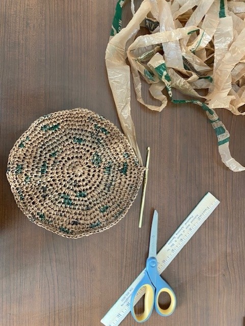 Plarn basket bottom with crochet hook, scissors, ruler and plarn