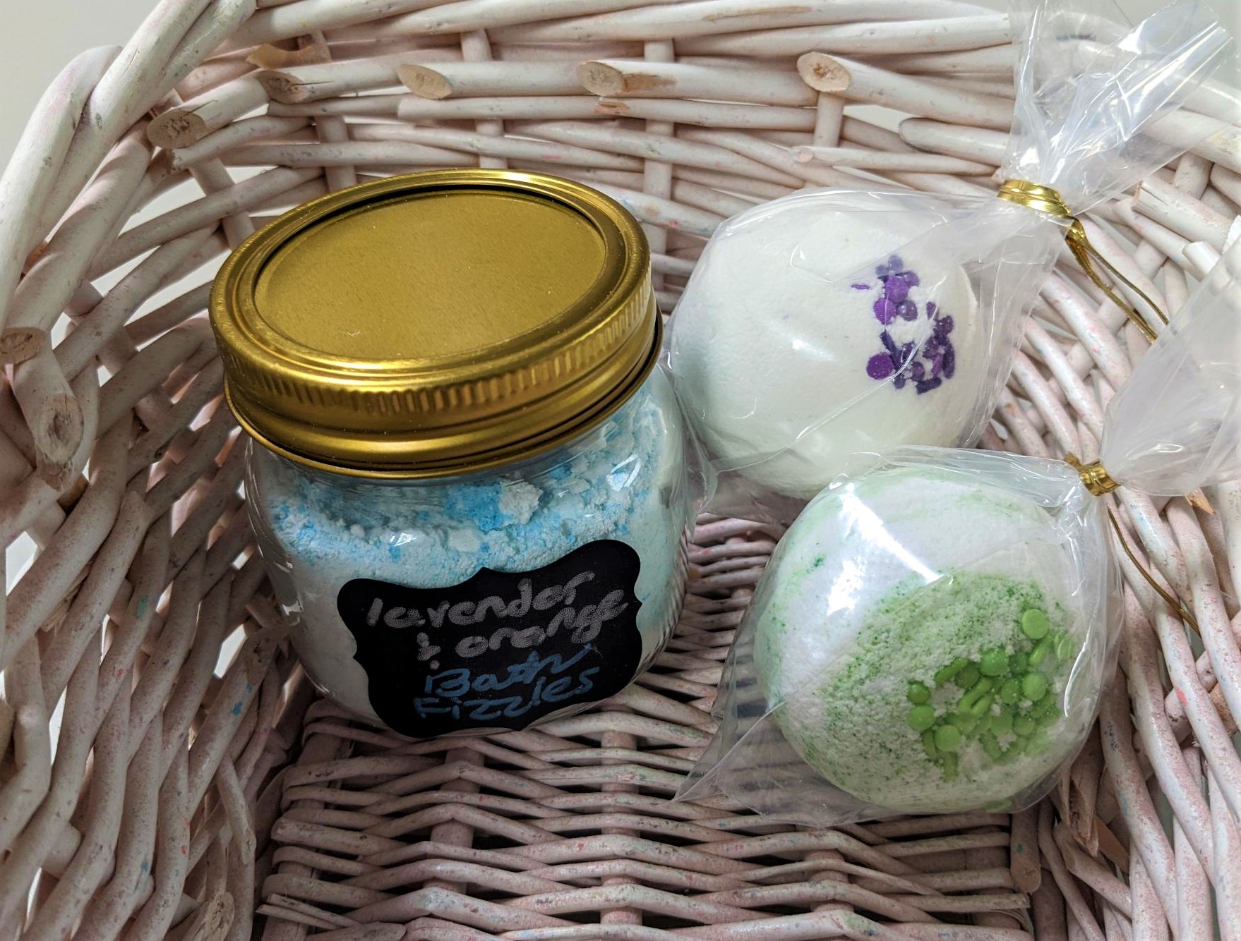 jar of blue and white bath fizzies, white bath bomb with purple sprinkles, and green and white marbled bath bomb
