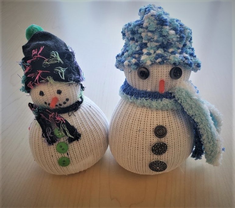 two snowmen made out of socks in blue scarves