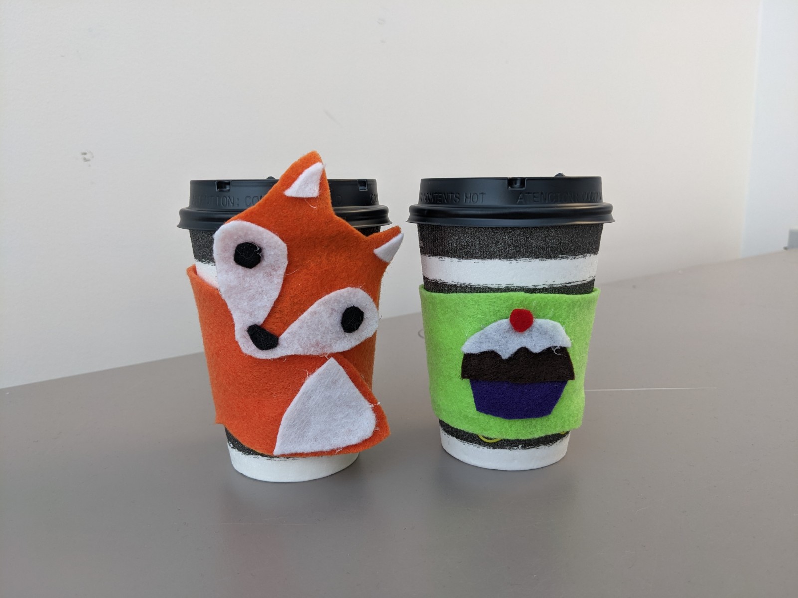 fox cozy on coffee cup and cupcake on green cozy on coffee cup