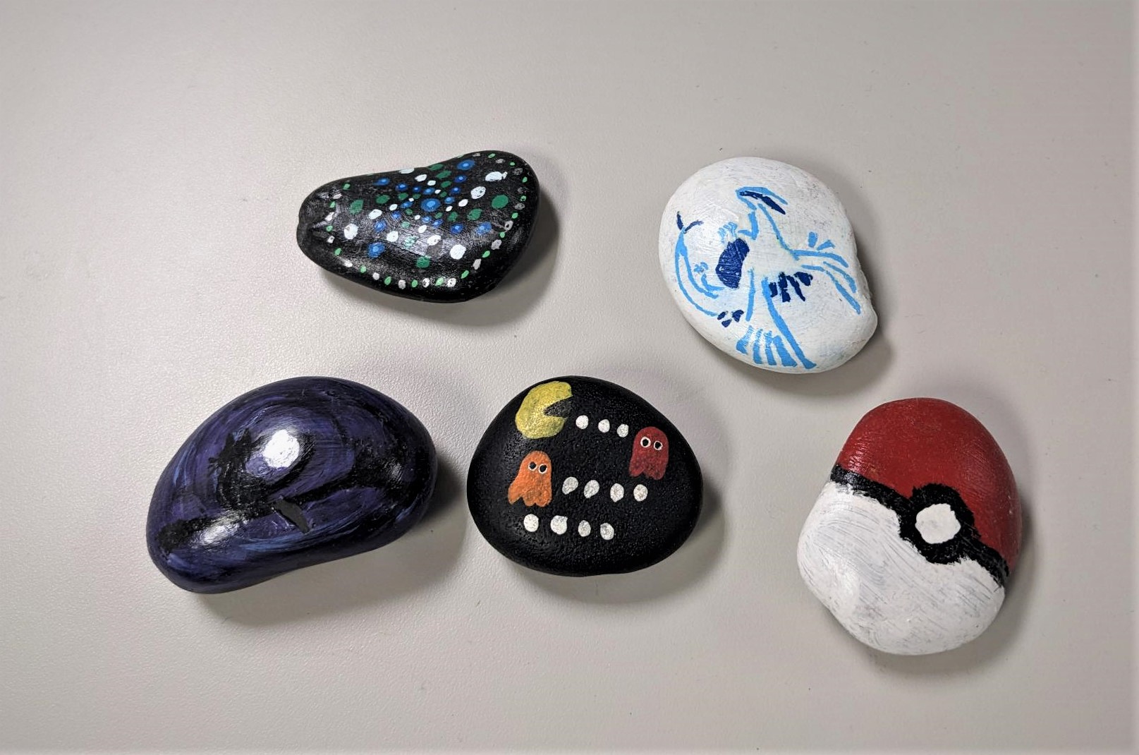 painted rocks with image of cat in a tree, dot art, Pac Man, Lugia, and Pokeball