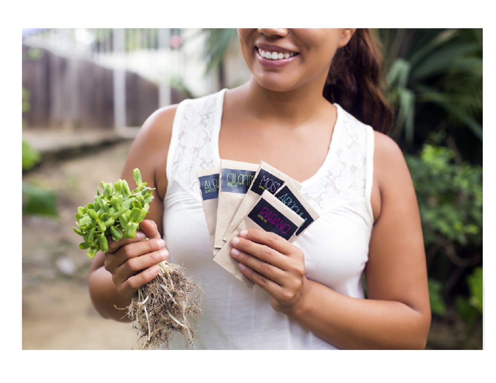 Woman with seed packets in one hand, plants in the other hand