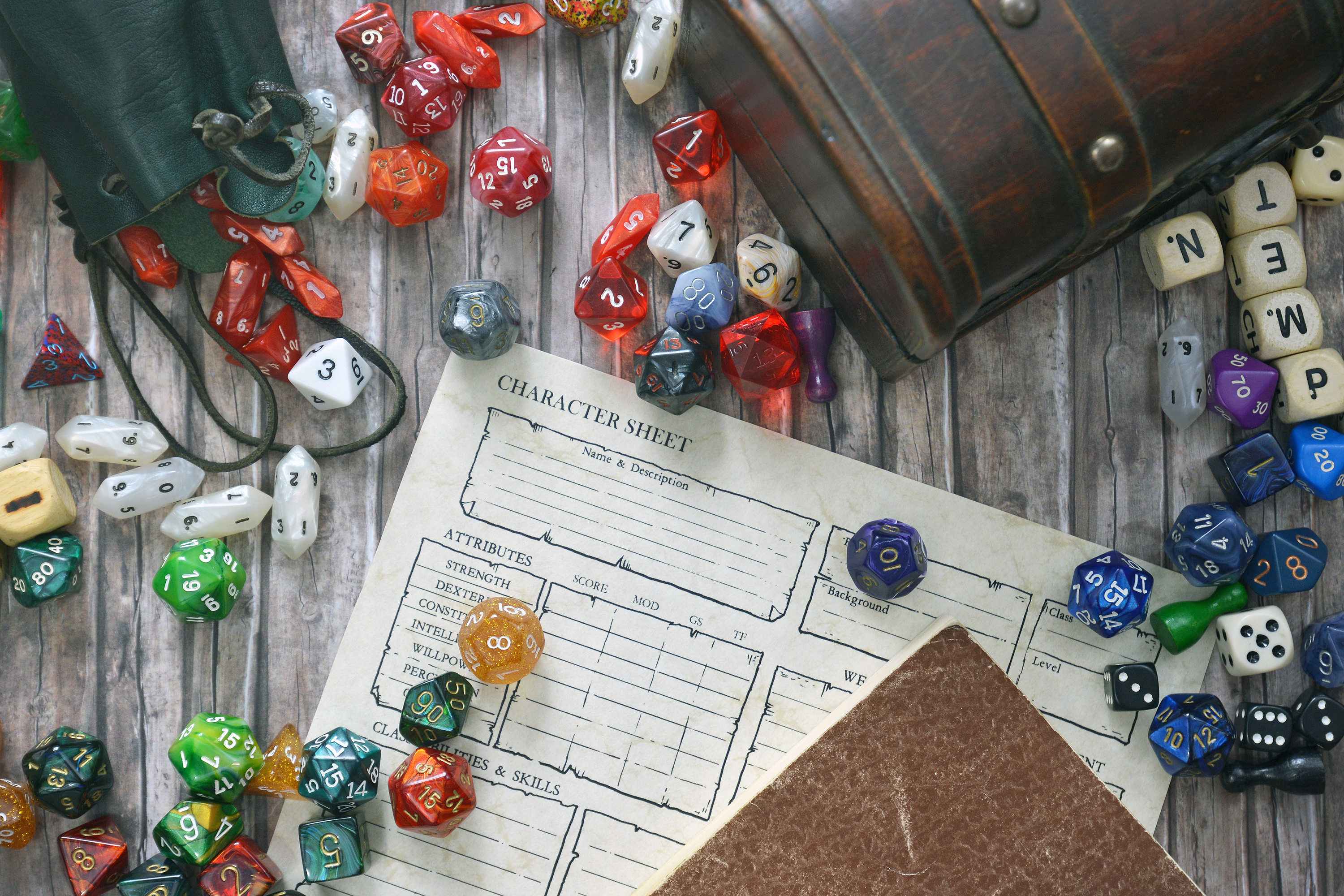 Tabletop role playing flat lay with colorful RPG and game dices, character sheet, rule book and treasure chest on wooden desk