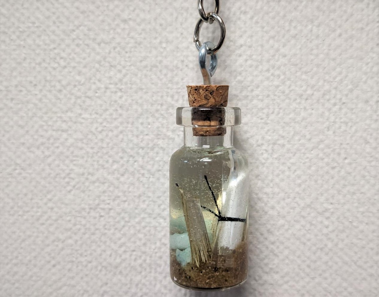 tiny corked bottle with message, sand, gravel, and plant piece