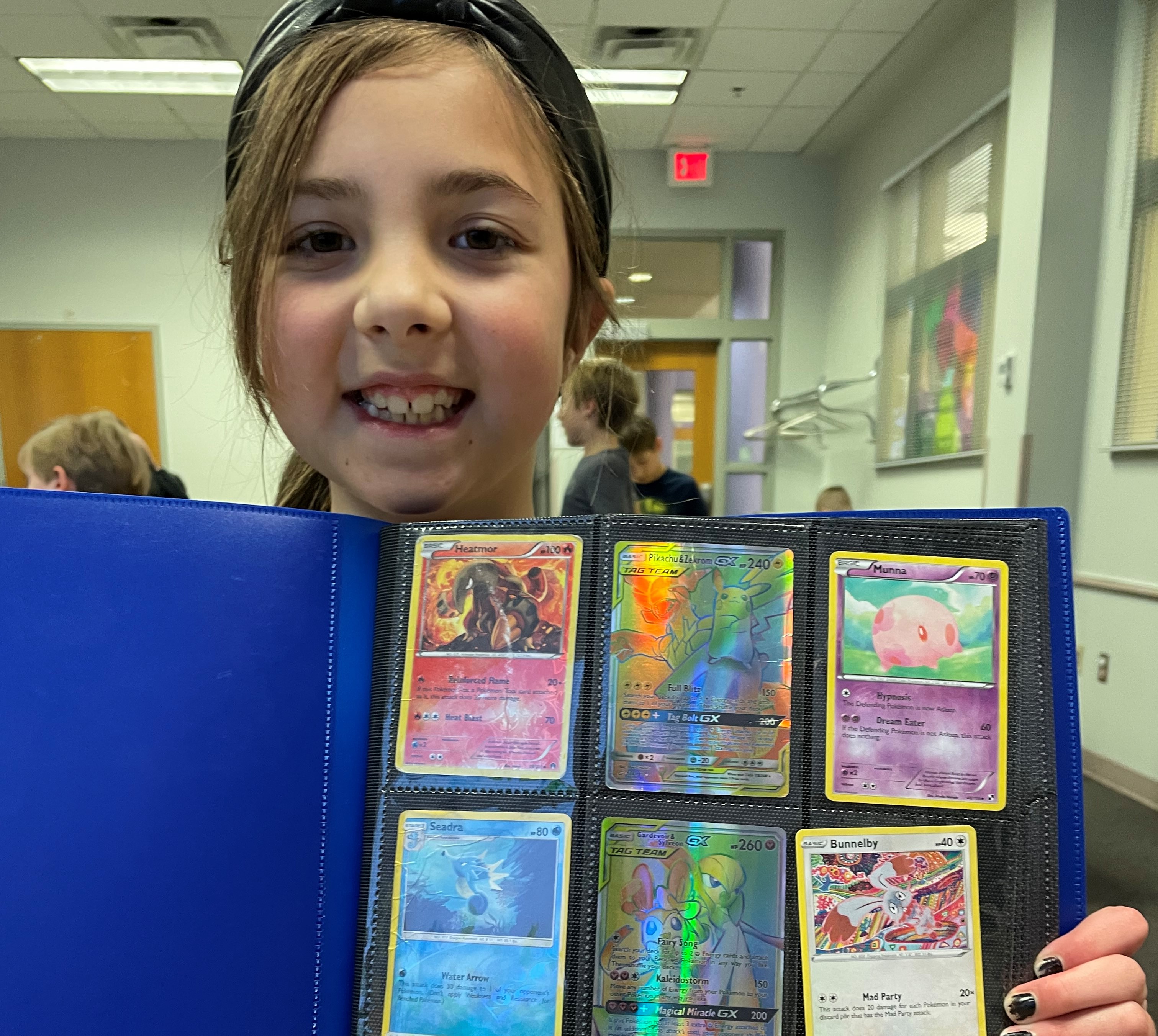 Young girl smiling showing her binder of Pokemon Cards