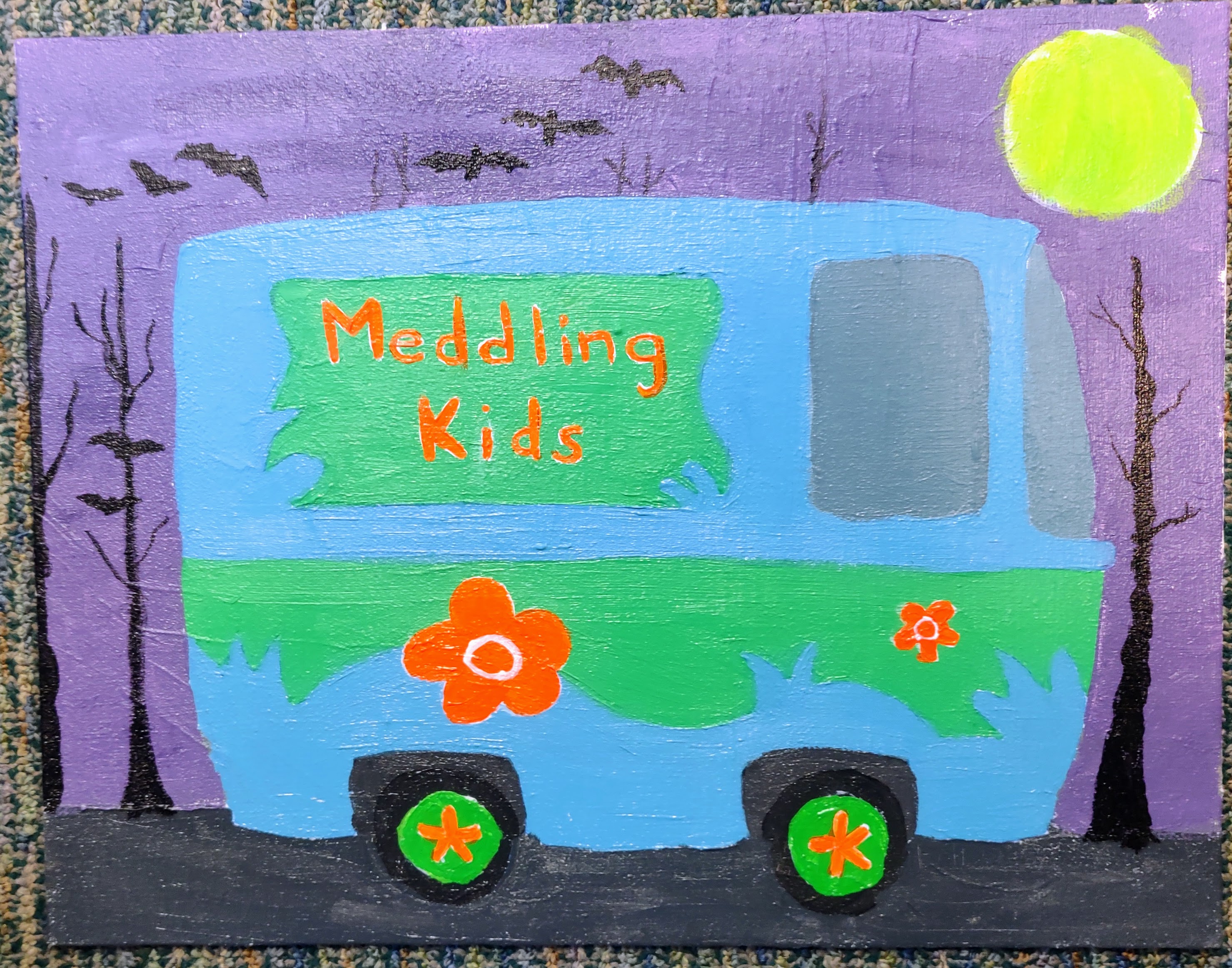 A painting of a blue and green van with orange flowers and the text Meddling Kids on the side. The background is a light purple with black trees, black bats, and a neon yellow green moon.
