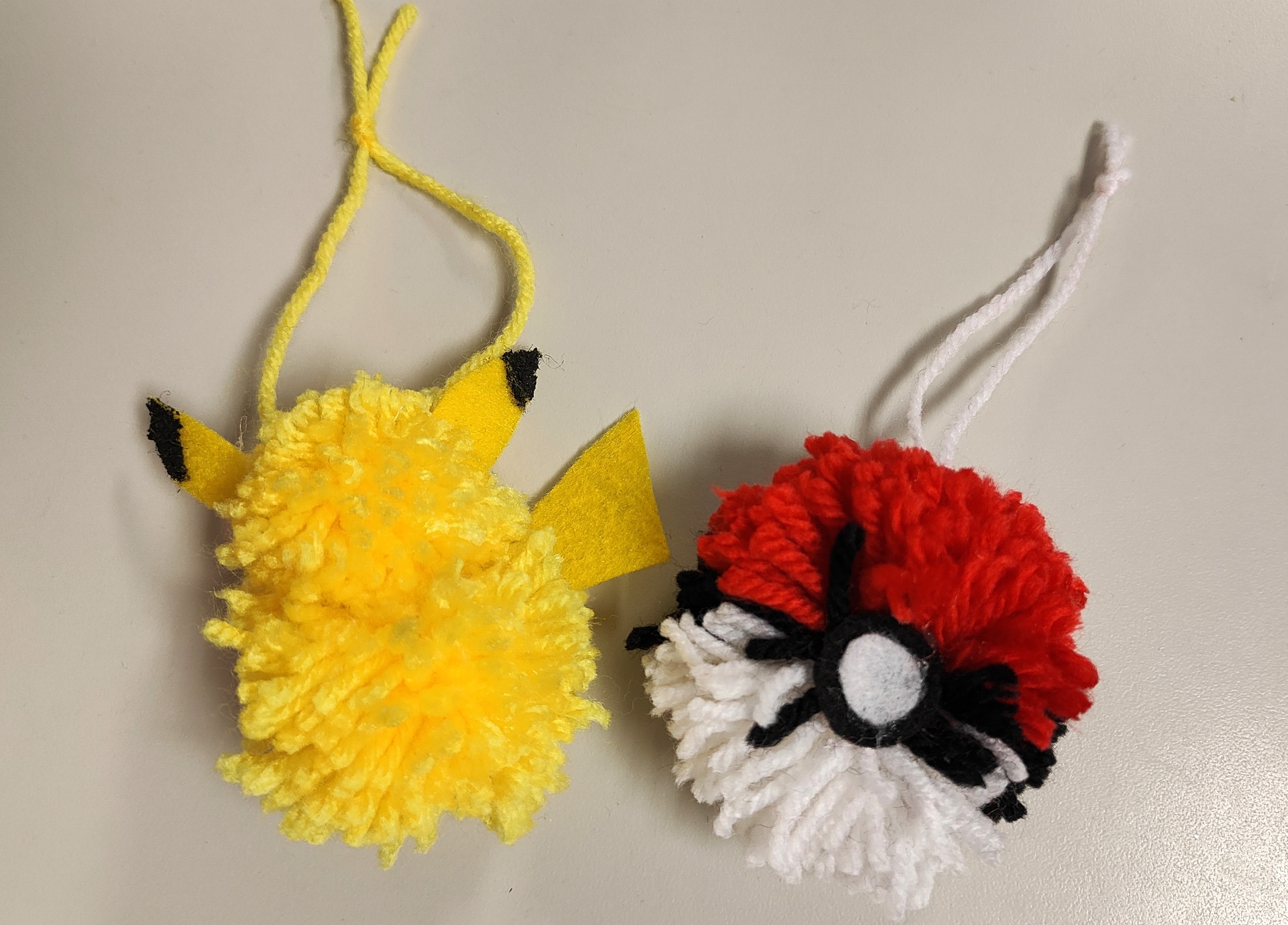 yellow Pikachu pompom and red and white Pokeball pompom