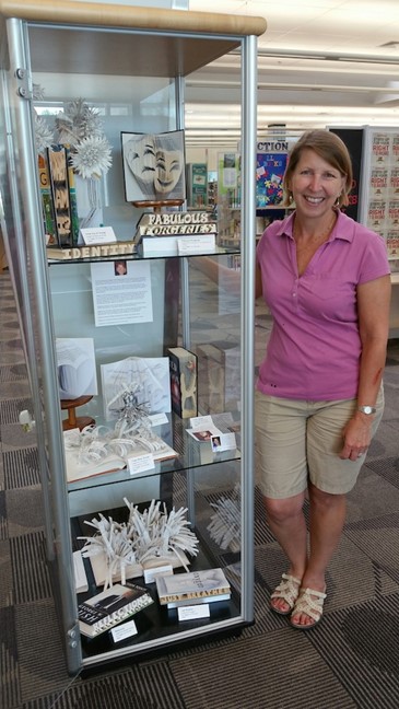 Artist Maggie Kerrigan next to a case of book art