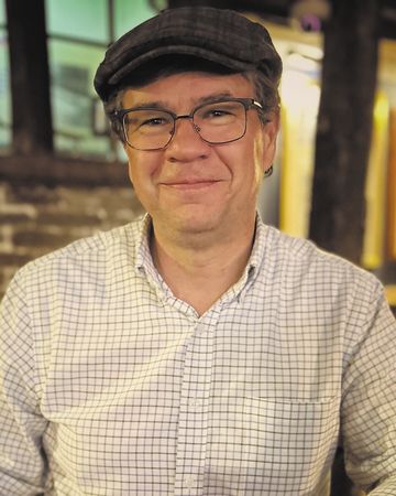 A headshot of author Deron Hicks smiling.