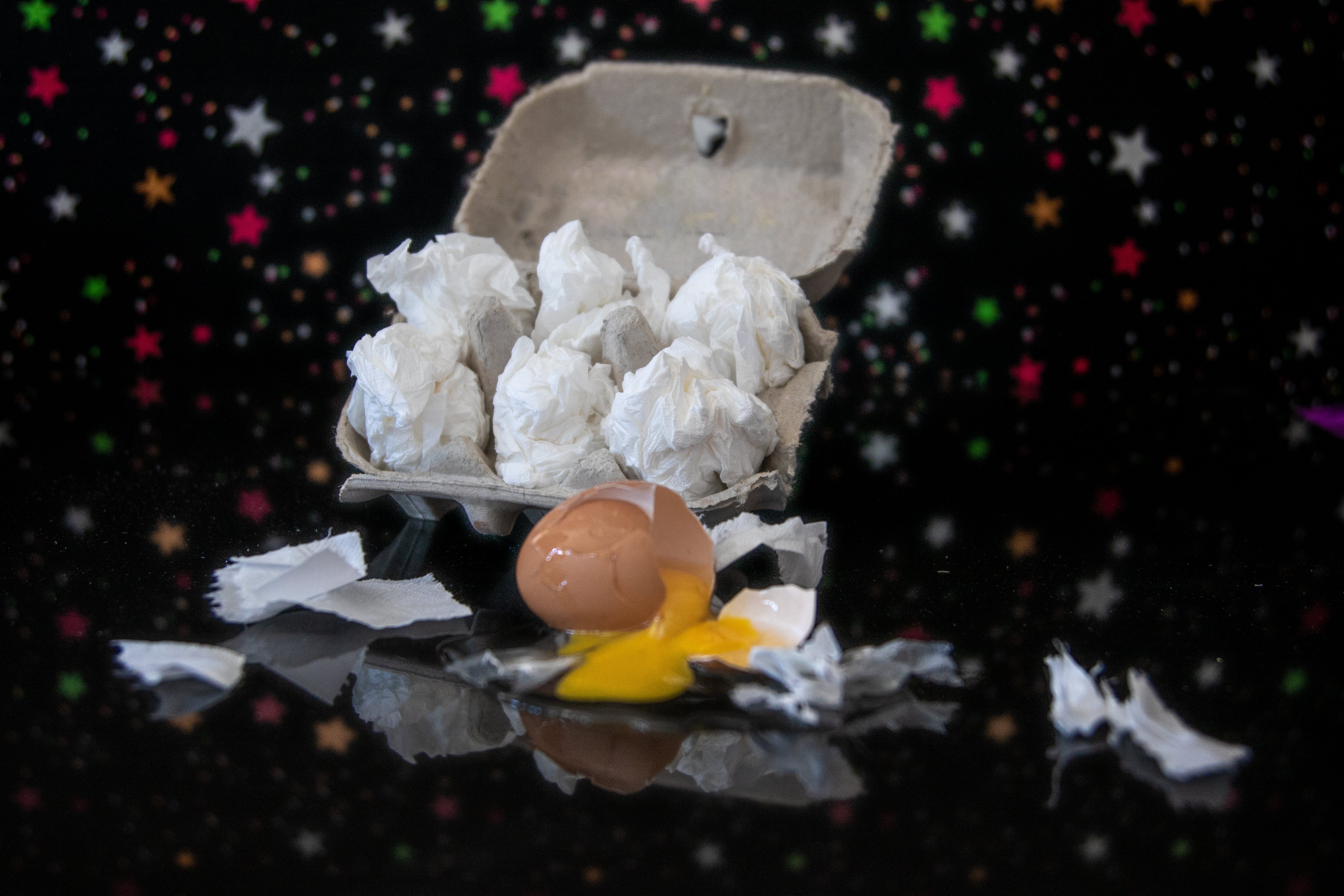 egg carton with cracked egg against a black background
