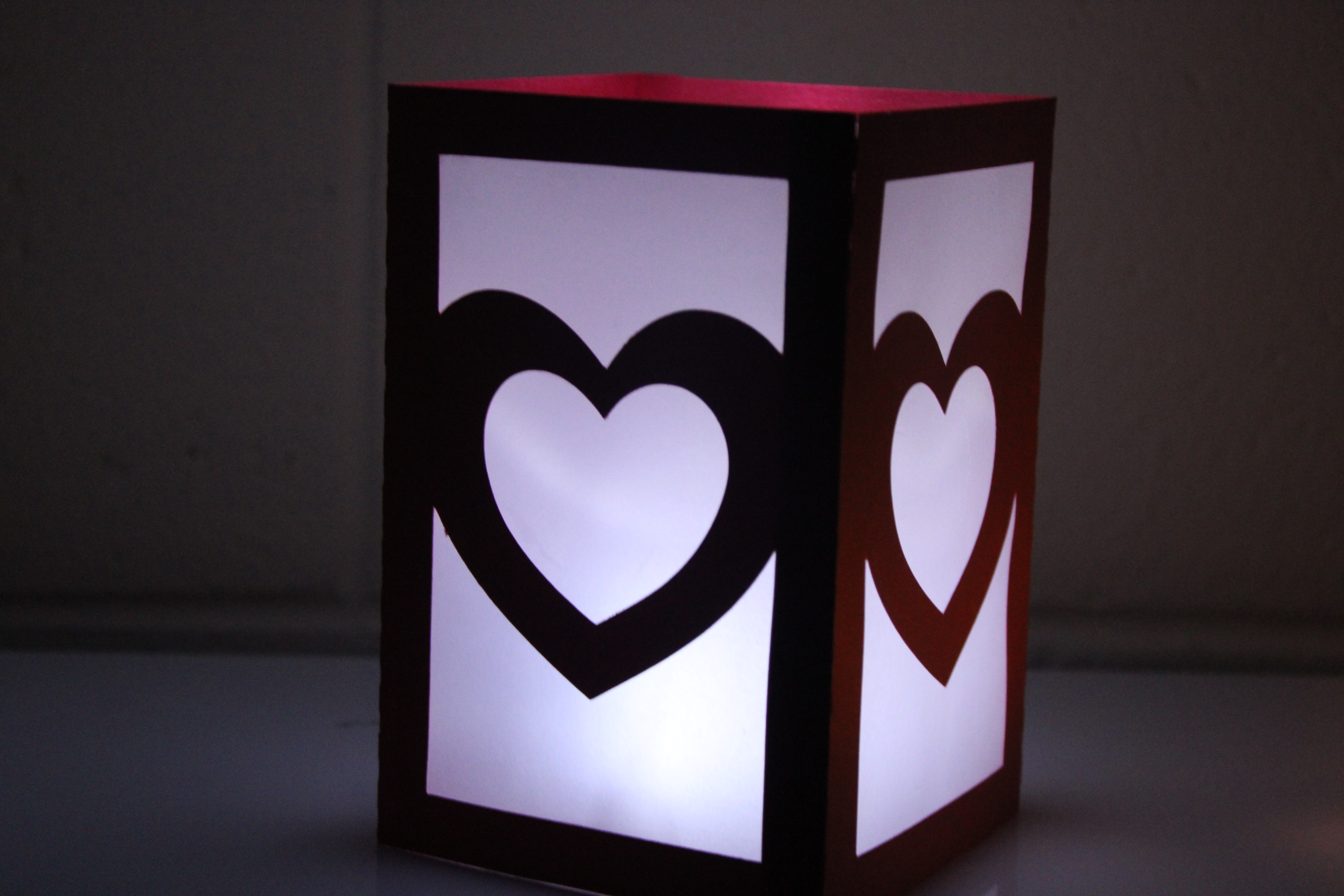 red four sided paper luminary with vellum windows. heart in the center of each side of the luminary.