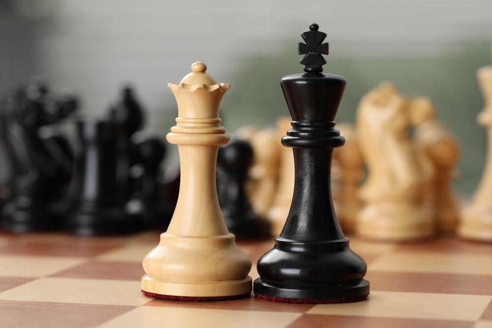 white wooden queen and black wooden king on chess board close up