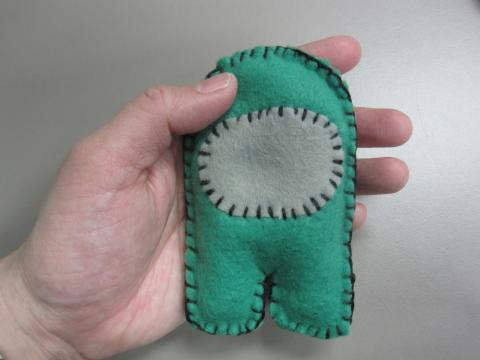 hand holding a green felt Crewmate handwarmer