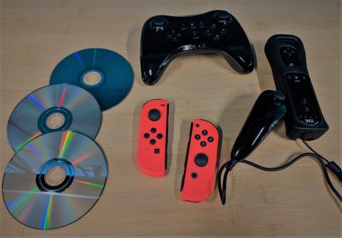 discs, red Switch Joy-cons, black video game controller, black Wii controllers