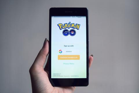 hand holding a phone with the Pokémon Go sign in screen showing