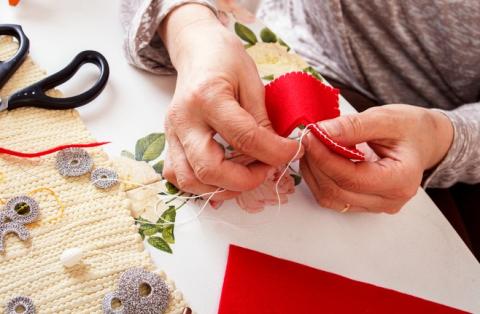 hands stitching on red fabric