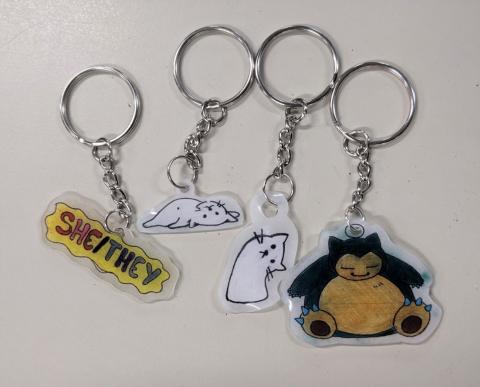 keychain with "she/they" pronouns, 2 cat key chains, and a Snorlax keychain
