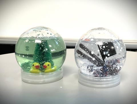 snowglobe with 2 yellow ducks and green tree and another snowglobe with snowman parts