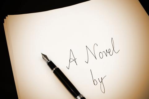 Paper and pen with the written words "A Novel By"