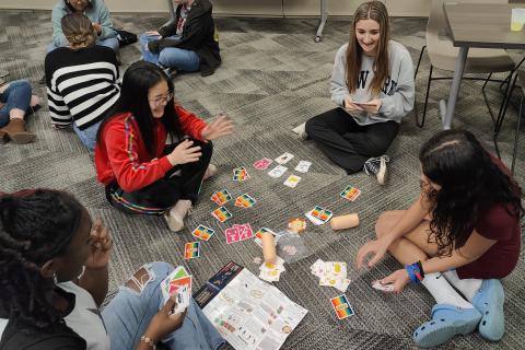 4 teens playing Throw Throw Burrito card game on the floor