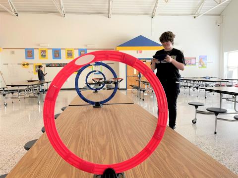 Teen flies a drone through a red hoop