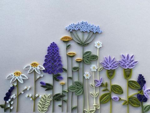 picture of quilled purple and lavender flowers lined up against gray background