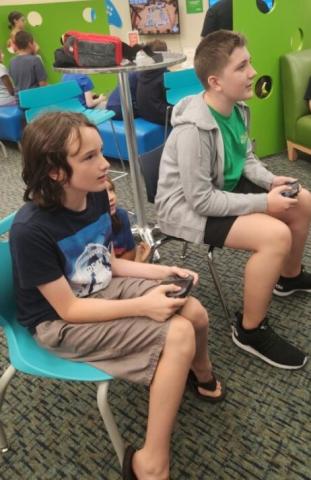 2 teens playing video games in teal chairs