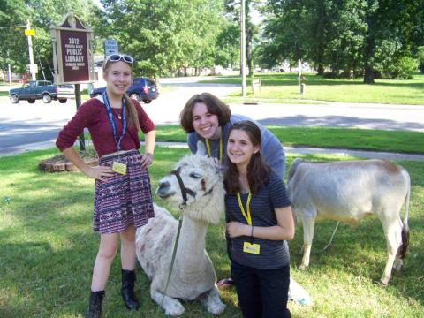 Three smiling teens and 2 farm animals