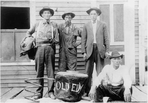 Chap Osborne, F. M. McGlothlin, _____ Webb, and Sam Davidson (sitting on porch) with moonshine still captured at Mud Lick in 1927