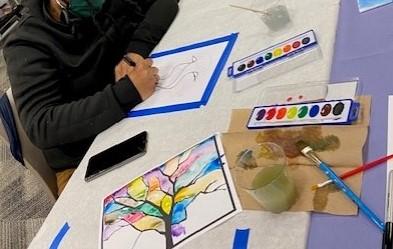 Person painting with art materials on the table 