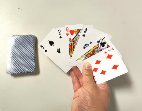 stack of playing cards and hand holding cards