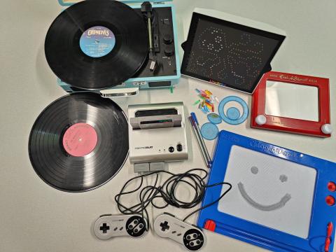 record player with record, extra record, Retro Duo gaming system with cartridge, Lite Brite, small pile of Lite Brite bulbs, spiral art pieces, Magna Doodle, and Etch a Sketch
