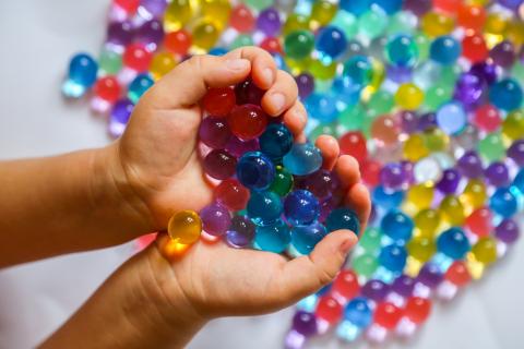 Colored balls of hydrogel in children's palms. Sensory experiences