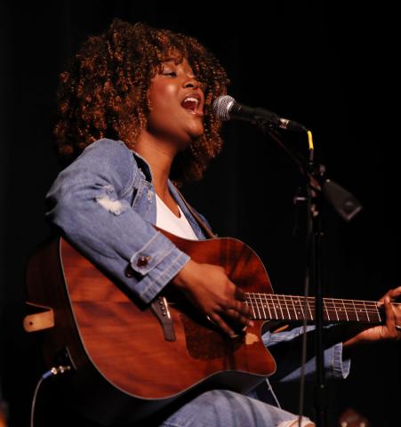 picture of woman Robert Lea playing guitar and singing while seated