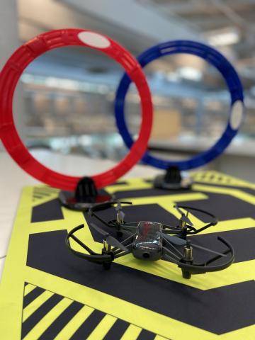 A drone on a landing pad with two rings in the background.