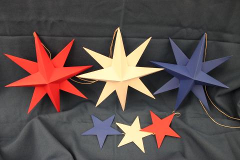 Red, white, and blue paper stars on a blue fabric backdrop