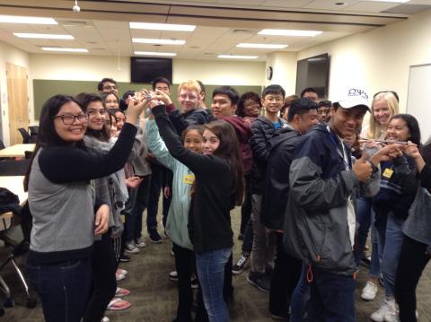 A crowd of teens doing a teambuilding activity in two groups.