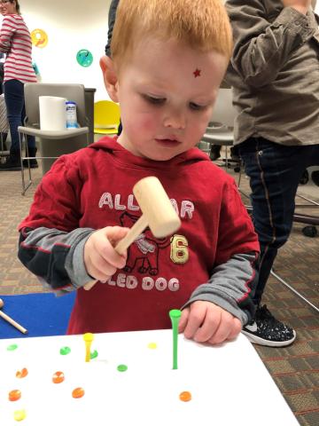 child hammering golf tees with wooden mallet