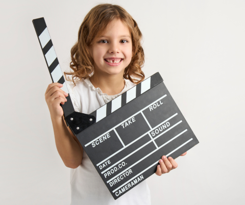 Child holding a clapperboard which is used on film sets