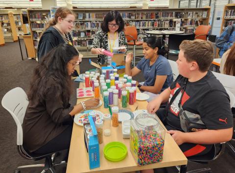 A group of teens sorting Perler bead at a table.