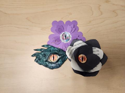 Green clay dragon eye, black and white paper flower with dragon eye, and purple paper flower with dragon eye.