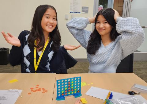 Two girls playing mini Connect 4.